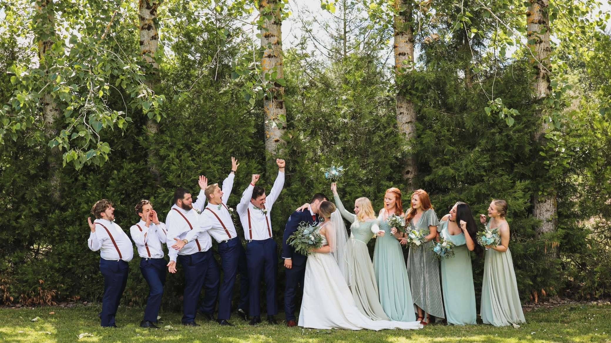 Le cortège d’un mariage lève les bras ensemble, dans un jardin