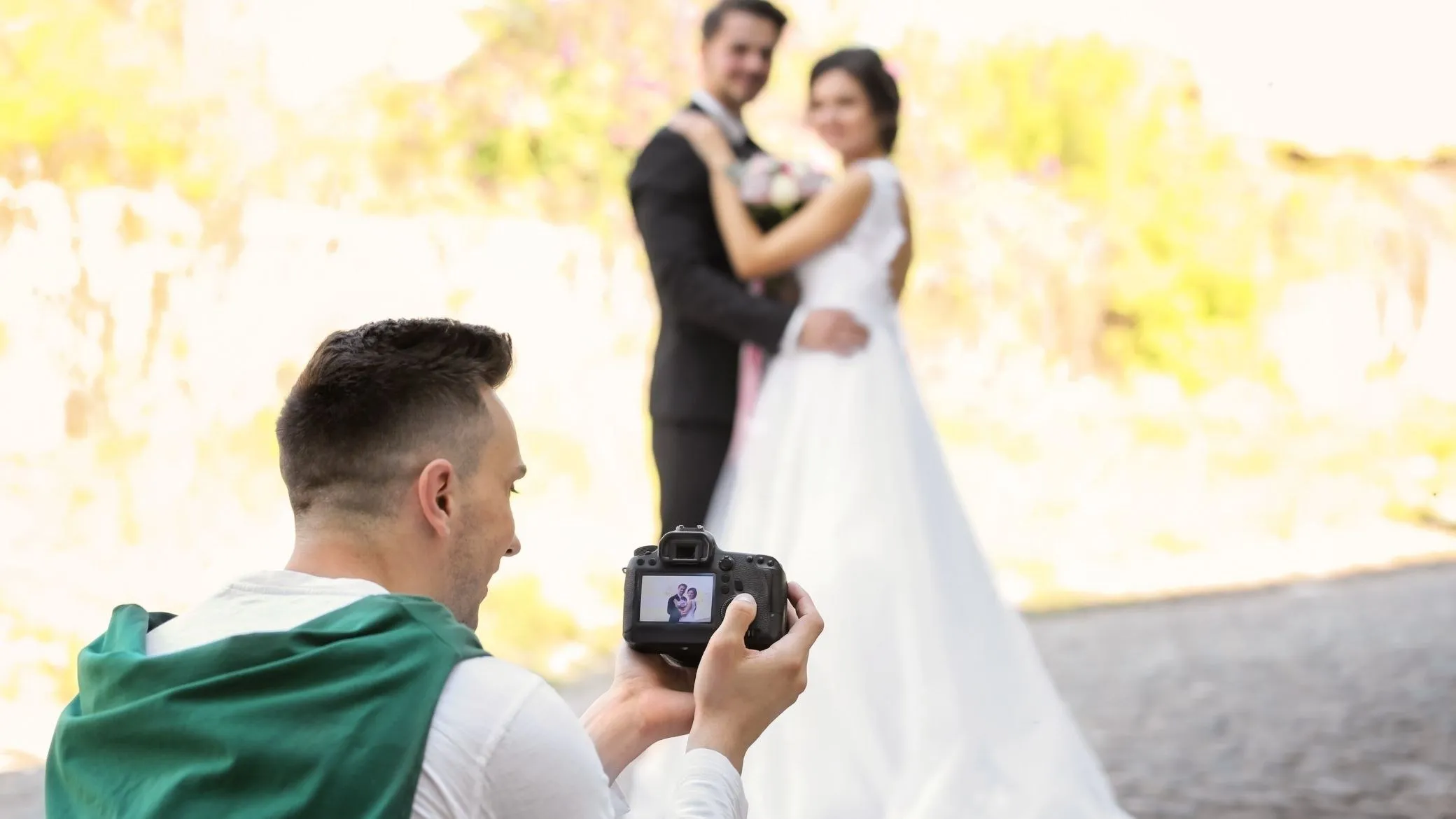 Un invité à genoux photographie les mariés avec un reflex