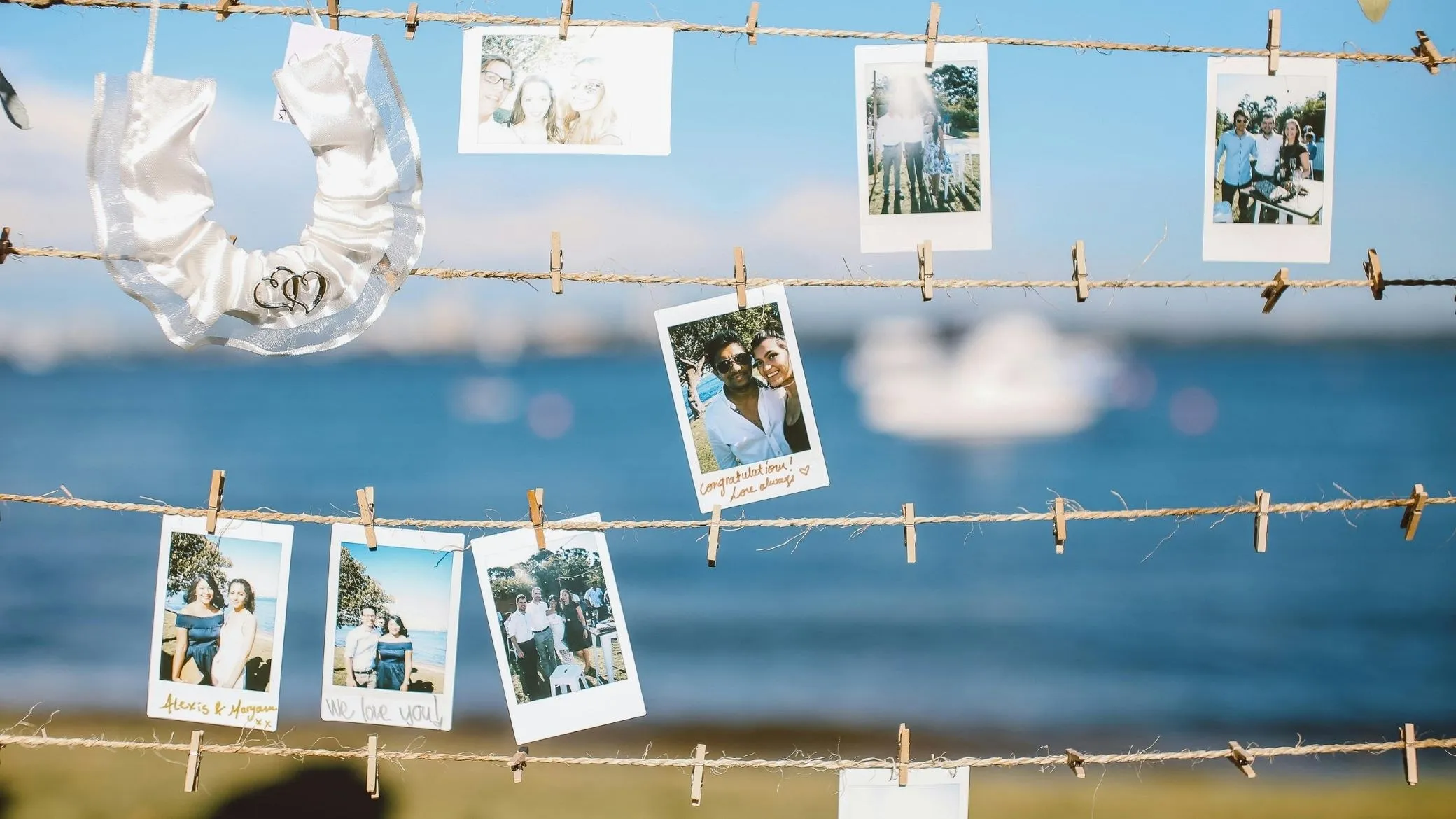 Des polaroïds accrochés à une ficelle avec des pinces, au bord de l’eau