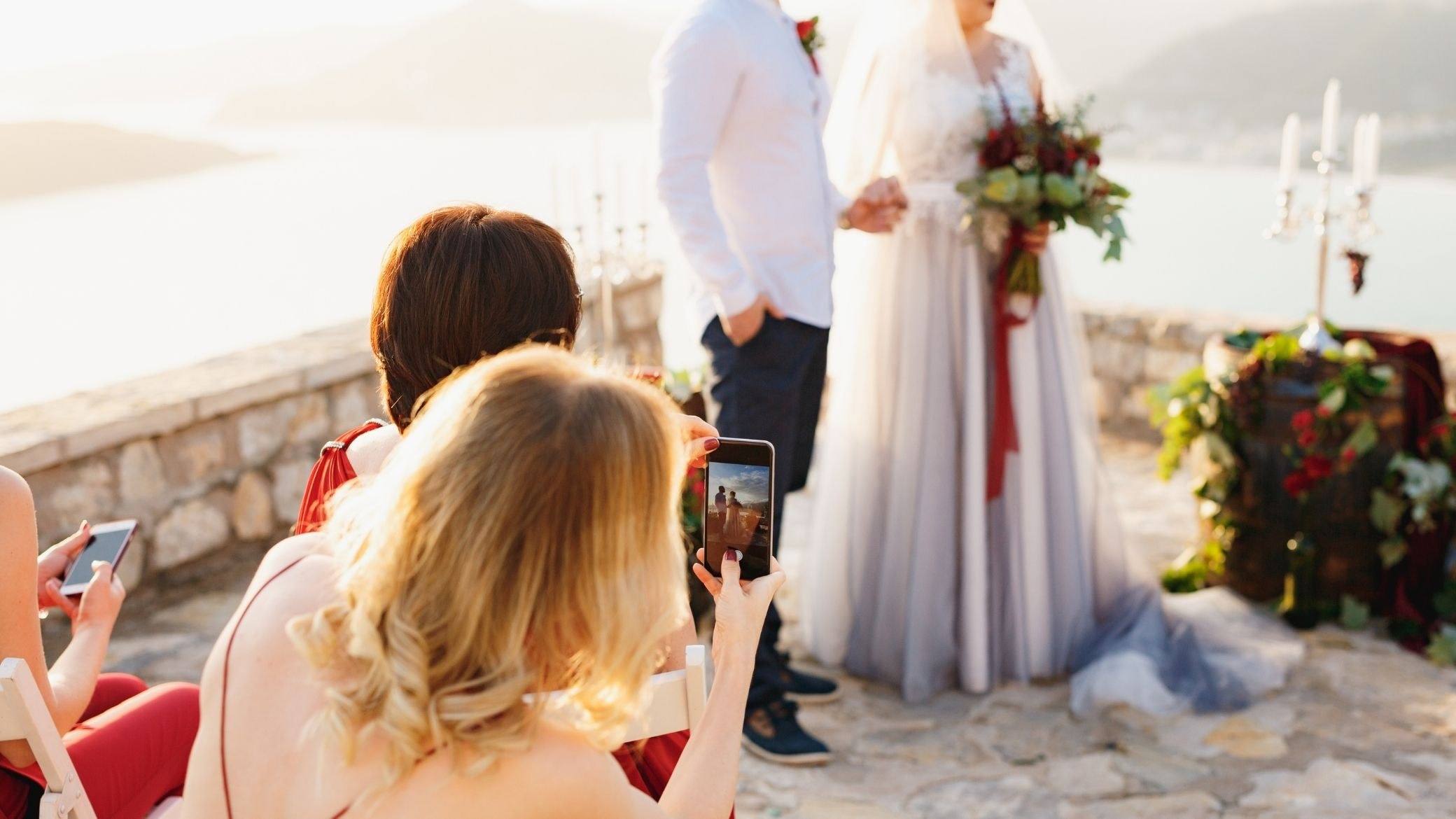 Des invitées photographient la mariée avec leur téléphone